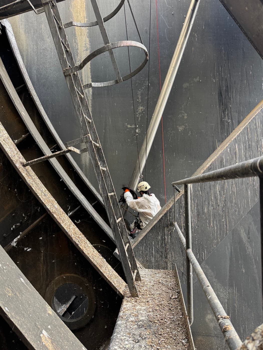 Técnico em suspensão no interior da ranhura de uma comporta da barragem, junto à haste de manobra.