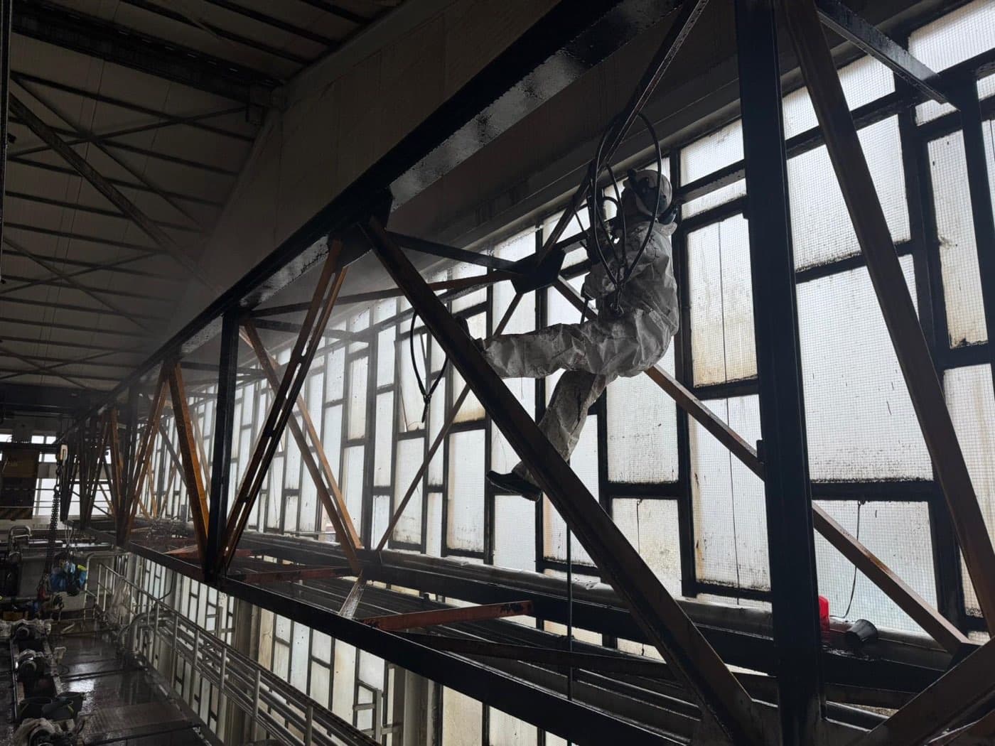 Trabalhos em altura sobre a viga da ponte rolante, no interior da unidade industrial.